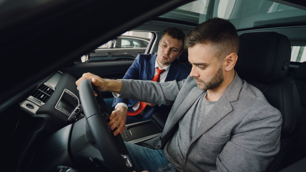 Handlowiec w salonie samochodowym korzysta z laptopa przy biurku